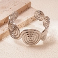 Close-up of a silver spiral circular textured open cuff bracelet on travertine stone - Silver