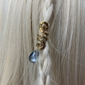 Close-up of golden spiral hair accessory with blue crystal pendant in braided hair - Blue Grey Pendant