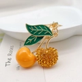Dettaglio di un portachiavi a ciliegia con smalto arancione e strass dorati brillanti - Arancione