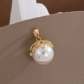 Macro shot of white round pearl pendant with textured gold crown cap on leather background - Gold Crown Artificial Pearl