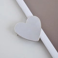 Dettaglio di un fermaglio per capelli a forma di cuore argentato su fondo bianco - Cuore Lucido / Argento