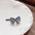 Close-up of a silver Y2K bow hair clip with blue rhinestones on a decorative plate - Bow / Blue
