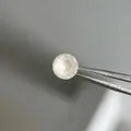 Sparkling round cut clear white cubic zirconia earring variant held by metal tweezers - 6mm Linen White AB (Single Piece)