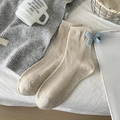 Beigefarbene Wollsocken mit blauer Strickschleife für Damen in gemütlicher Heimumgebung - Einheitsgröße / Beige