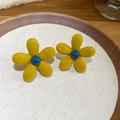 Macro detail of yellow flocked flower earrings with blue centers on a wooden tray - Yellow