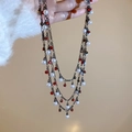 Detail einer mehrlagigen dunklen Halskette mit weißen Perlen und roten facettierten Perlen - Schwarz Rot Perlen Layering Stil