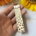Dettaglio ravvicinato di portachiavi in pelle con stampa leopardata e gancio dorato - Punto Oro Beige