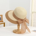 Detailed close-up of woven straw texture and linen bow on beige wide-brim sun hat - Straw Peak Beige