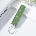 Green rhinestone 3-section pill organizer keychain on a white decorative stand - Green