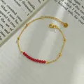 Detail of minimalist gold-plated stainless steel chain with shiny red faceted beads - Red Faceted Bead / Red