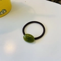 Macro shot of polished dark green oval bead on a durable black elastic hair tie - Jelly Green
