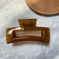 Close-up of a large amber rectangular resin hair claw clip with a glossy translucent finish - Jelly Coffee