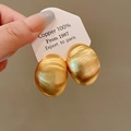 Detail of gold oval earrings made of 100% copper with a brushed metallic texture - 100% Pure Copper Brushed Oval / Gold Semi-wrapped Round