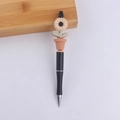 Dettaglio del ciondolo a girasole sopra una penna a sfera in plastica nera elegante - Beige