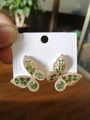 Macro shot of gold butterfly earrings with emerald gemstones and micro zircon stones - 14K Gold Green Zirconia