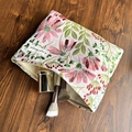 Canvas makeup bag with pink floral embroidery and a top zipper on dark wood background - Galsang Flower Beige