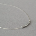 Detailed close-up of 7 minimalist grey pearls on a gold-plated brass necklace chain - 7 Grey Pearls / Silver