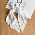 Detail van een witte satijnen haarelastiek met lange linten op een minimalistisch bureau - Puur Wit Satijnen Lint