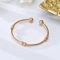 Detail of gold-plated stainless steel cable wire cuff bracelet with spherical sliding beads - Style 2 / Gold