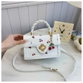 Detail der weißen Handtasche mit Kirschdruck, floralem Goldverschluss und gedrehtem Griff - Gebrochenes Weiß