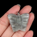 Handheld view of a 30x35mm natural grey labradorite butterfly pendant with stone texture - Labradorite
