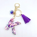 Letter K resin keychain with purple tassel and colorful stones on a white background - Letter K