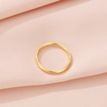 Vista superior detallada de un anillo de oro minimalista sobre un fondo de tela rosa texturizada - US 6 / Dorado
