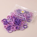 Nahaufnahme von lila und rosa elastischen Haargummis im Beutel mit Gänseblümchen-Print - 50 Stück/Packung (Beutel) / Lila Serie