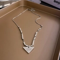 Zilveren ketting met gegraveerde driehoekige hanger en kralen op een bruine display - Zilveren Geometrische Letter