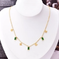 Gold butterfly necklace with rectangular green gemstones on an elegant display model - Green Rhinestone Butterfly