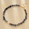 Detailed close-up of blue stone beaded necklace with pearl and gold chain on silk - Blue Aventurine