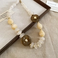 Detail of acrylic irregular beads necklace with gold spacers on vintage wooden frame - Necklace-White