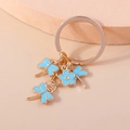 Creative keychain featuring gold metal ring with light blue dragonflies and flower charms - Blue