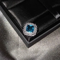 Makroaufnahme eines Blumenrings mit quadratischem blauen Edelstein und weißen Diamanten - Seeblau Zirkonia Ring (Verstellbar)