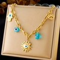 Detail view of gold sun and Hamsa pendants with blue evil eye beads on a jewelry pad - Fatima Hand Evil Eye Style (N3230)