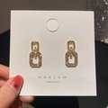 Détail de boucles d'oreilles géométriques dorées serties de zircons scintillants - Doré