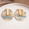 Detail view of 18k gold plated U-shaped earrings with blue marble acetate pattern on ceramic - Blue White Marble