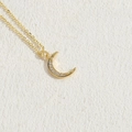 Elegante collana a mezzaluna dorata con pavé di zirconi su fondo materico caldo - Oro Piccolo