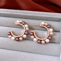 Close-up of C-shaped gold earrings with white, champagne, and purple pearls in a velvet box - C-Shaped Half Hoop Pearl Earrings - Purple - Light Coffee Gold - Champagne