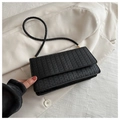 Sac à bandoulière noir tissé minimaliste présenté sur un blazer beige élégant et chic - Noir