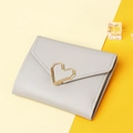 Detail of grey faux leather wallet with gold heart clasp on a clean yellow background - Gray