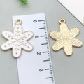 White enamel snowflake charm with gold plating shown next to a ruler for size - White Snowflake 19x24mm
