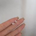 Minimalist S925 sterling silver bow knot stud earring held in fingers for scale - Hollow Bowknot / Silver