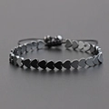 Bracciale regolabile in ematite nera con perle a cuore e cordino intrecciato su sfondo grigio - Cuore