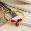 Detailed shot of adjustable red enamel strawberry pendant bracelet with golden beads - Strawberry Pendant Style (E000445YS)