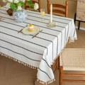 White linen tablecloth featuring black stripes and tassels on a wooden dining table - 140-260 / Black & White Stripes
