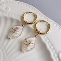 Close-up of 18K gold hoop earrings with cream glass pendants and pink rose detail - Gold-White