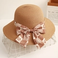Elegant straw sun hat with decorative letter-printed bow on a minimalist display - Camel