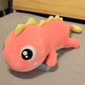 Peluche dinosaure rose avec ailerons jaunes, oreiller doux posé sur un lit confortable - 110cm / Dragon allongé rose