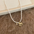 Dettaglio della collana di perle con ciondolo a forma di cavallo a dondolo dorato e zircone - Collana - Oro - Bianco